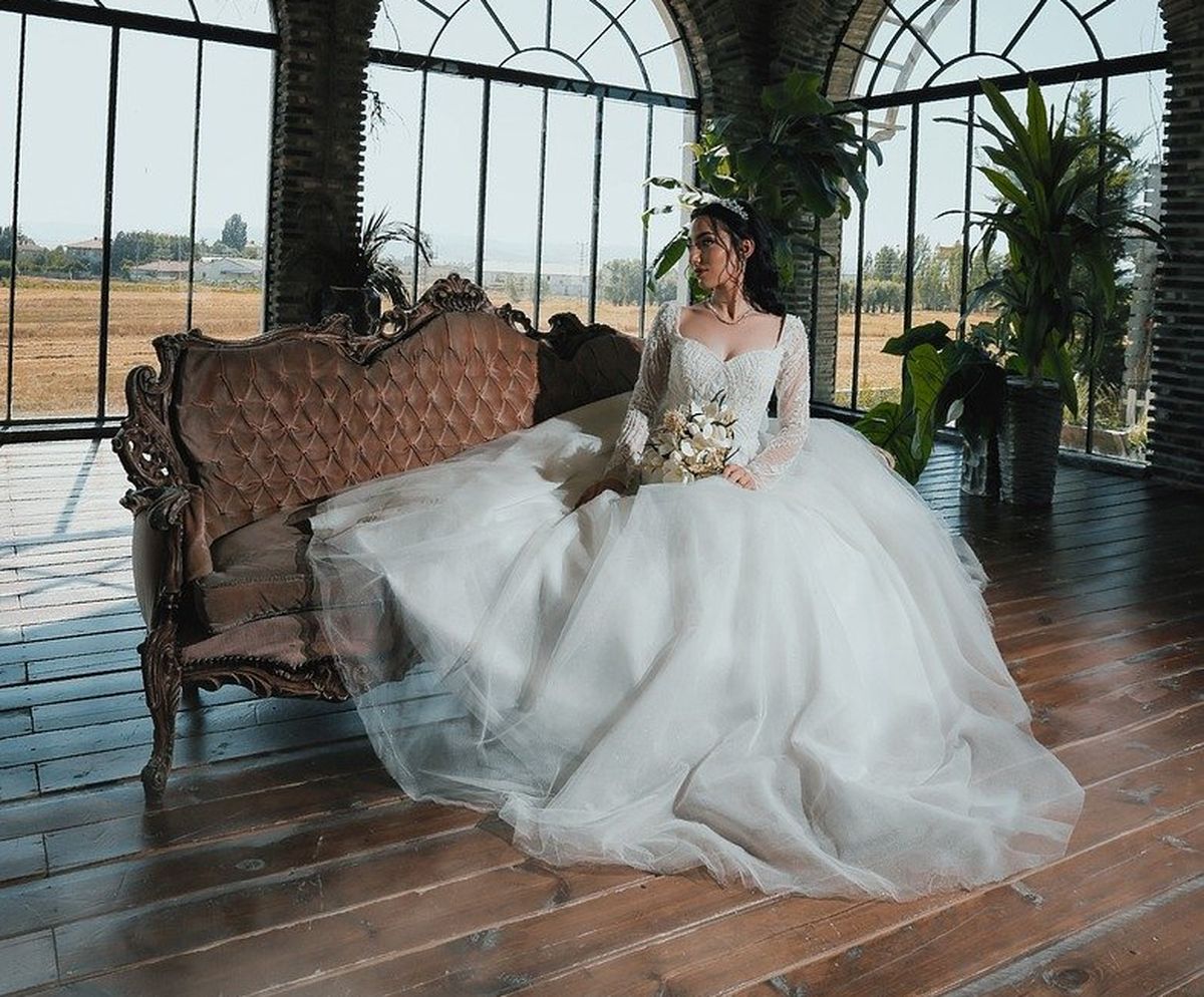 bride ina flowing gown sitting on antique love seat